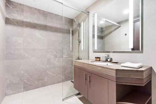 a bathroom with a sink and a shower with a mirror at Silkhaus Beautiful 1BDR Near Reem Central Park in Abu Dhabi