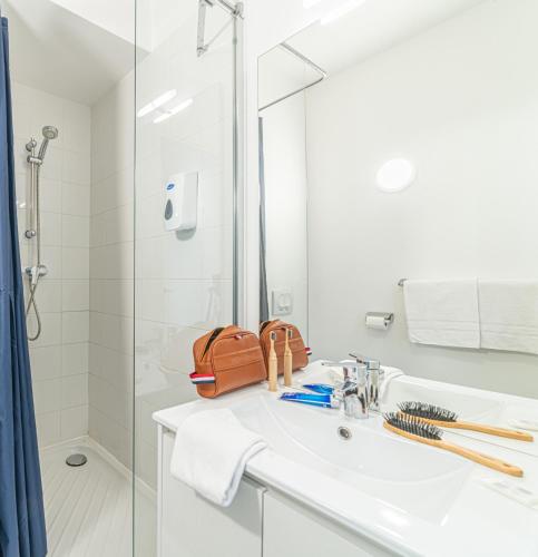 une salle de bain avec un lavabo et une douche dans l'établissement Montempô Marseille Centre Dôme, à Marseille