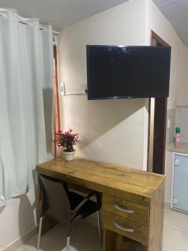 a room with a desk with a television on the wall at Quitinete Cordeirense in Cordeiro