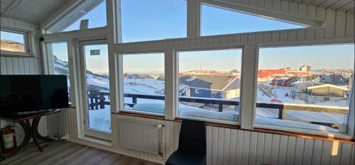 a room with windows with a view of a snowy mountain at Ilulissat Hostel in Ilulissat