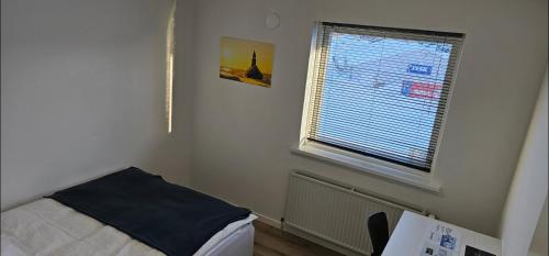 a small bedroom with a bed and a window at Ilulissat Hostel in Ilulissat