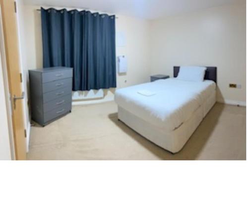 Mead House في Thamesmead: غرفة نوم بسرير وخزانة وستارة زرقاء