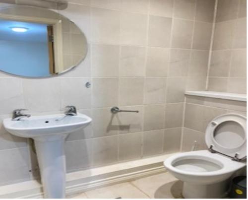 a bathroom with a toilet and a sink and a mirror at Mead House in Thamesmead