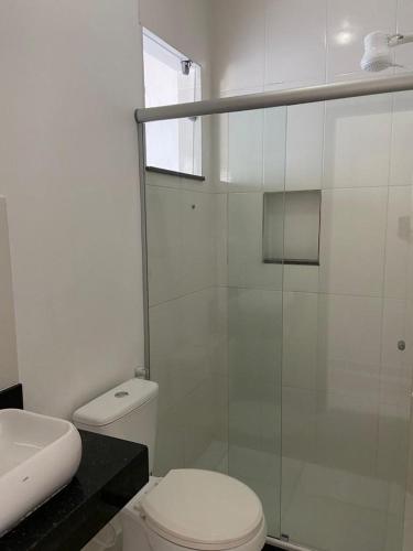 a bathroom with a toilet and a glass shower at Oceano Suítes in Arraial do Cabo