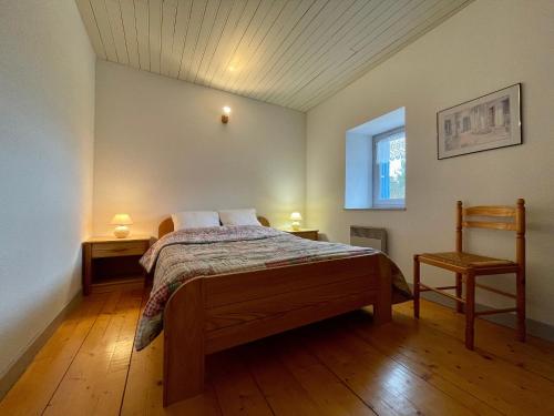 ein Schlafzimmer mit einem Bett, zwei Tischen und einem Stuhl in der Unterkunft Gîte Saint-Pierre-du-Champ, 5 pièces, 8 personnes - FR-1-582-61 in Saint-Pierre-Duchamp