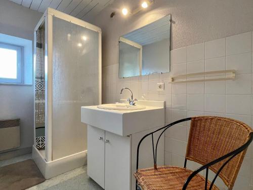ein Badezimmer mit einem Waschbecken, einem Spiegel und einem Stuhl in der Unterkunft Gîte Saint-Pierre-du-Champ, 5 pièces, 8 personnes - FR-1-582-61 in Saint-Pierre-Duchamp