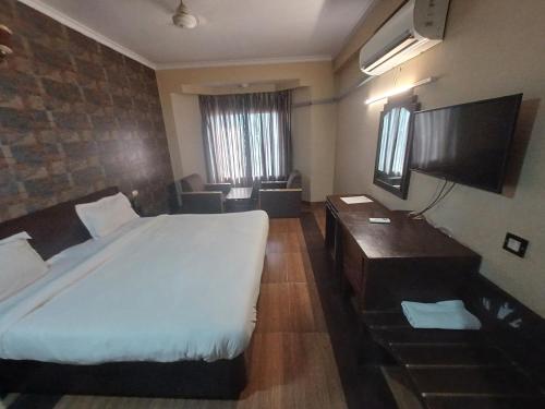 a bedroom with a large white bed and a desk at Hotel Maya international in Jaipur