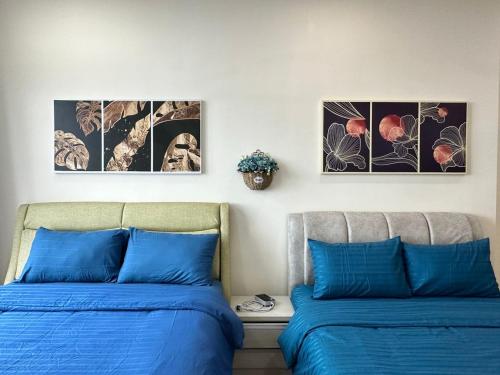 two beds in a room with three pictures on the wall at Cozy couple apartment suite in Masai