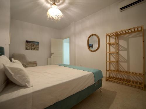 - une chambre avec un grand lit blanc et un miroir dans l'établissement au cœur de sidi bou said, à Sidi Bou Saïd