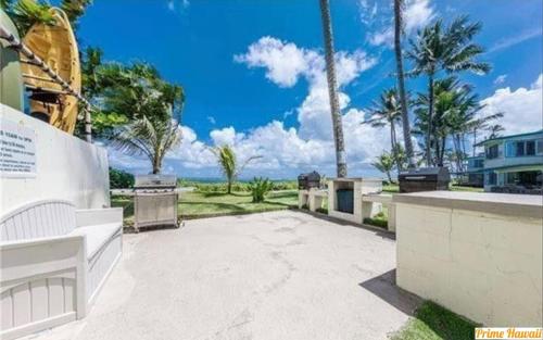 a patio with palm trees and a view of the ocean at Beautiful Condo Right on the Beach in Hauula