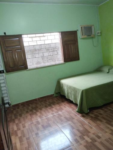 1 dormitorio con cama, ventana y suelo de madera en Casa Parintins, en Parintins