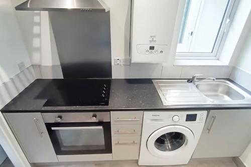 a kitchen with a sink and a washing machine at CNTRL Reading Modernized 3 bedroom House in Reading