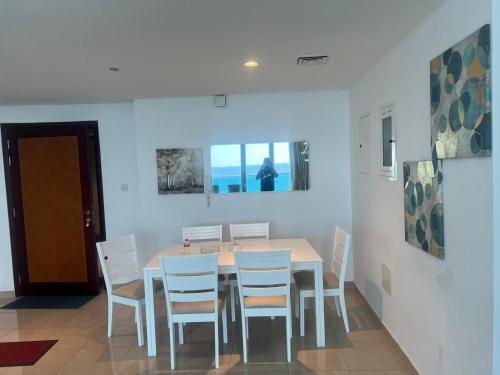 a dining room with a table and white chairs at Ocean View Luxury Suites in Ajman 
