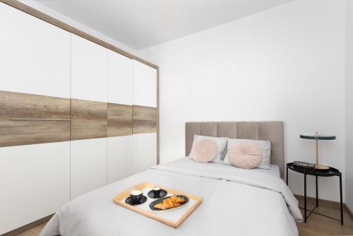 a white bed with a tray of food on it at Apartament Gocławska SWPS PGE Narodowy Dworzec Wschodni Soho Factory in Warsaw