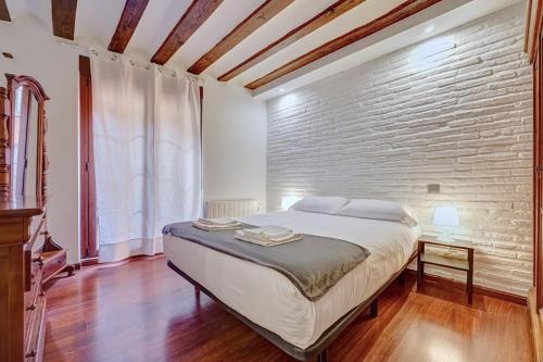 ein Schlafzimmer mit einem großen Bett und einer Ziegelwand in der Unterkunft Dúplex Portales By Clabao in Logroño