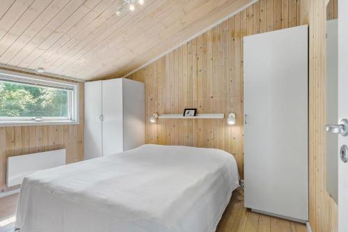 um quarto com uma cama branca e paredes de madeira em Little Fiskerbanke - Lovely, Private, And Family-friendly Holiday Home em Saltum