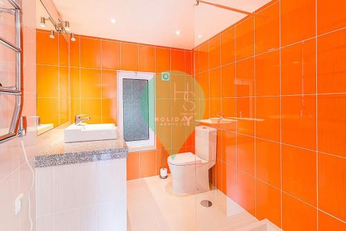 an orange bathroom with a toilet and a sink at Onde a Marina é Casa T2 HsRentals Vilamarina in Quarteira