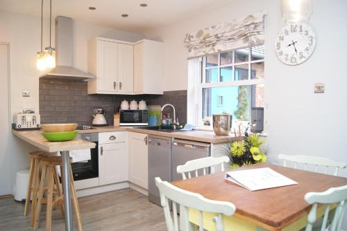 a kitchen with white cabinets and a wooden table at Secret Mersea Retreat - a stroll from the anchorage! in West Mersea