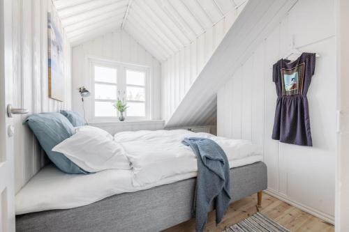 a bedroom with a bed with white sheets and blue pillows at Hawbakkens 3 Skønne Ferieboliger in Hjørring