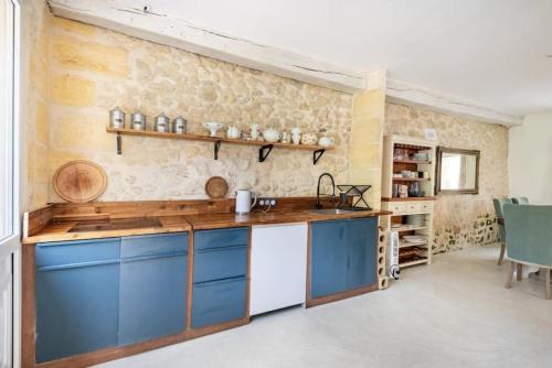 a kitchen with blue cabinets and a stone wall at Charmant cottage aux portes de l'entre deux mers in Cambes