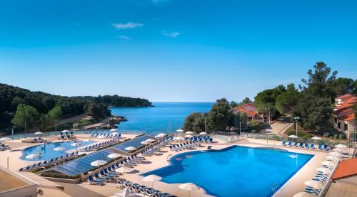 uma vista para um resort com uma piscina e cadeiras em Maistra Camping Porto Sole Pitches em Vrsar