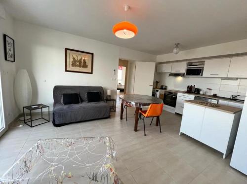un salon avec un canapé, une table et une cuisine dans l'établissement Maloya, à Sérignan