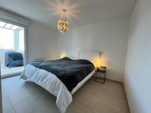 une chambre avec un lit et un lustre dans l'établissement Maloya, à Sérignan