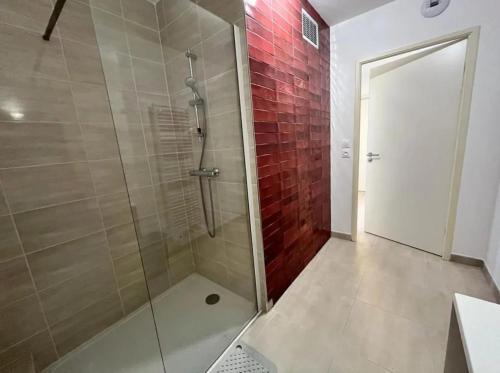 une salle de bain avec une douche avec une porte vitrée dans l'établissement Maloya, à Sérignan