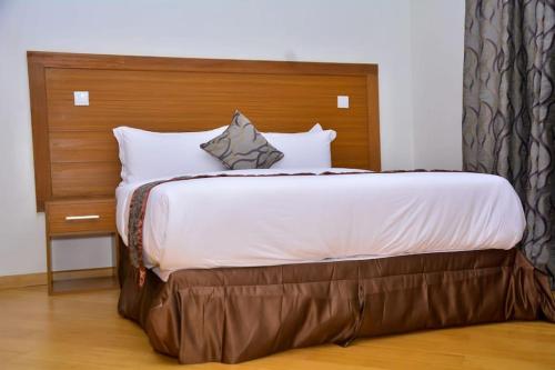 Schlafzimmer mit einem großen Bett mit einem Kopfteil aus Holz in der Unterkunft The Moon Apartments in Mutomo