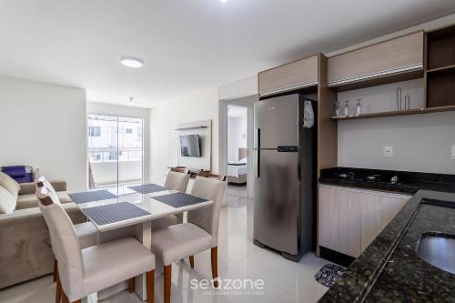 a kitchen and dining room with a table and a refrigerator at Apto c/ varanda loc. privilegiada em BC BFH0101 in Balneário Camboriú