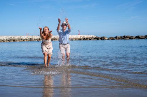 a man and a woman walking in the water at Appartamenti Villa Tonni in Gabicce Mare