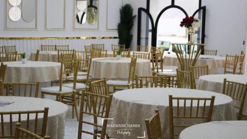 una habitación llena de mesas y sillas con mantel blanco en hotel amilcar tataouine, en Tataouine