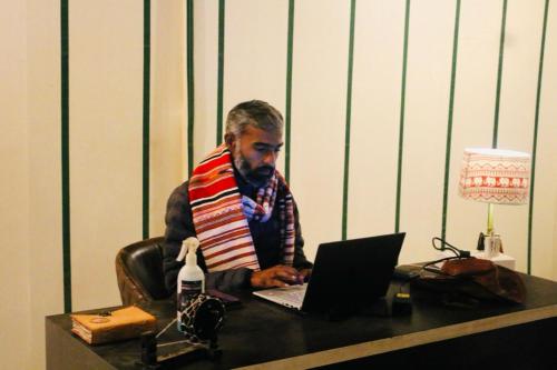 a man sitting at a desk using a laptop computer at Venture Desert Camp Jaisalmer in Jaisalmer
