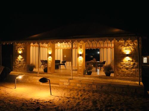 a stone house with lights in the yard at night at Venture Desert Camp Jaisalmer in Jaisalmer