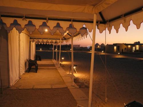 a tent with a chair under it at night at Venture Desert Camp Jaisalmer in Jaisalmer