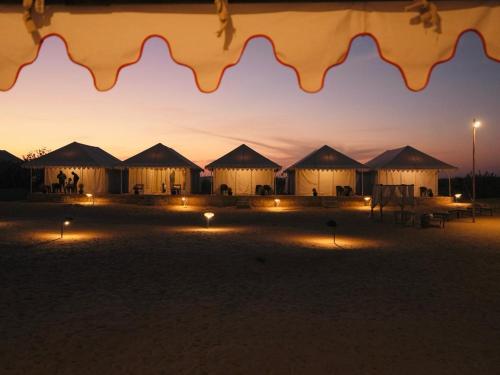 a group of tents in the desert at sunset at Venture Desert Camp Jaisalmer in Jaisalmer