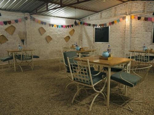 a dining room with tables and chairs and a tv at Venture Desert Camp Jaisalmer in Jaisalmer