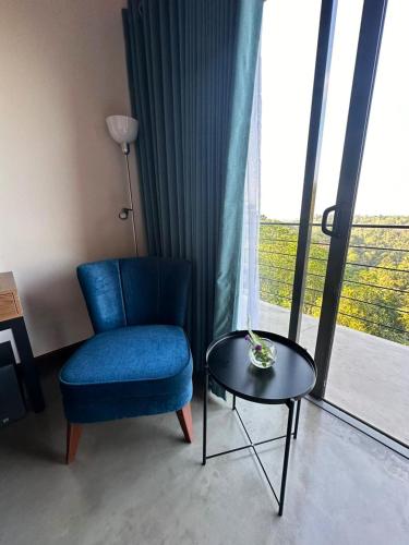 a room with a blue chair and a table and a window at Amore Resorts in Kobbekaduwa