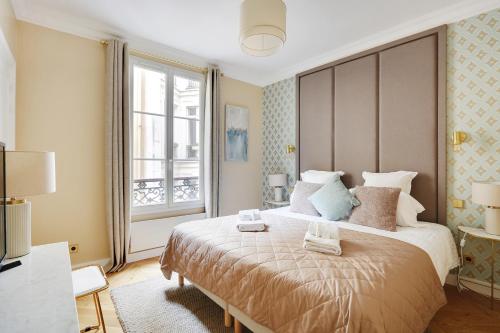 une chambre avec un grand lit avec une grande fenêtre dans l'établissement Pick A Flat's Apartments in Opéra Saint Lazarre - Rue de l'Isly, à Paris