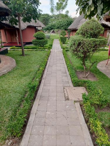 un chemin en pierre dans un jardin avec des maisons dans l'établissement Kamutamba guesthouse, à Masaiti