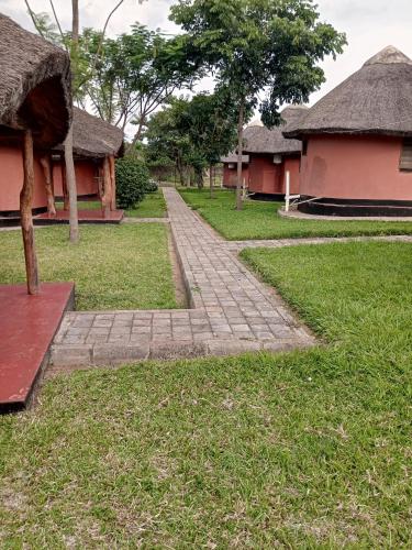 een bakstenen pad voor twee gebouwen met bomen bij Kamutamba guesthouse in Masaiti