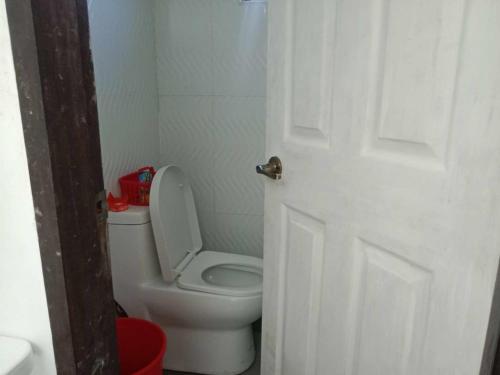a bathroom with a toilet and a white door at La Veranda Farm Breeze in Batuan