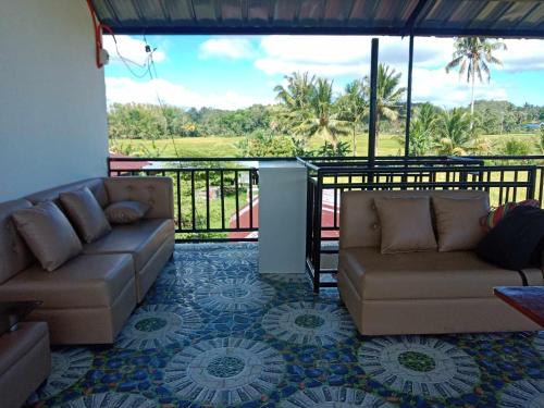 a living room with two couches and a balcony at La Veranda Farm Breeze in Batuan