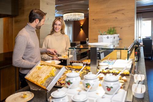 a man and woman preparing food in a buffet at Hotel Nordik Adults Only - Over 14 in Andalo