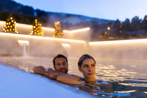 a man and woman swimming in a swimming pool at Hotel Nordik Adults Only - Over 14 in Andalo