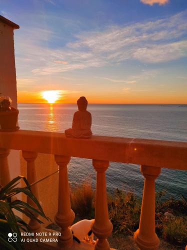 a person sitting on a rail watching the sunset at L'AUNISA in El Campello