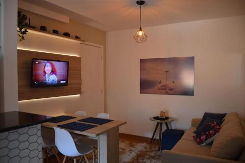 sala de estar con sofá y TV en la pared en Apartamento Marilândia Juiz de Fora, en Juiz de Fora