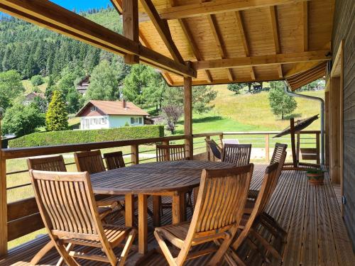 une table et des chaises en bois sur une terrasse dans l'établissement Gîte 4 étoiles à La Bresse, grand confort, proche station ski - FR-1-589-394, à La Bresse