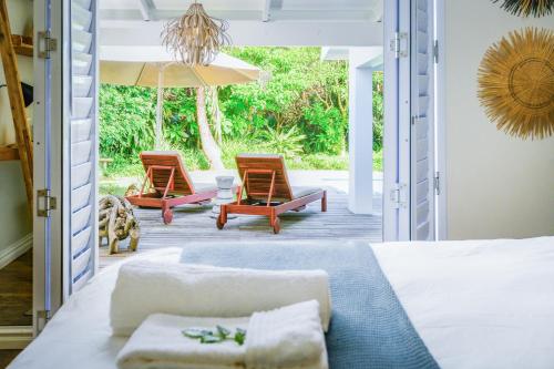 1 dormitorio con 1 cama, 2 sillas y 1 sombrilla en Luxury Private Beach Villa centrally located. en Westbrook