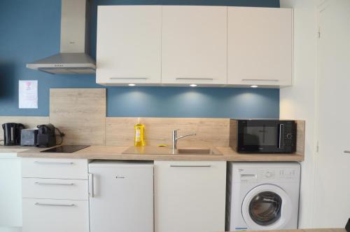 une cuisine avec des armoires blanches, un évier et un micro-ondes dans l'établissement Charmant studio, proche de tout, à Tours